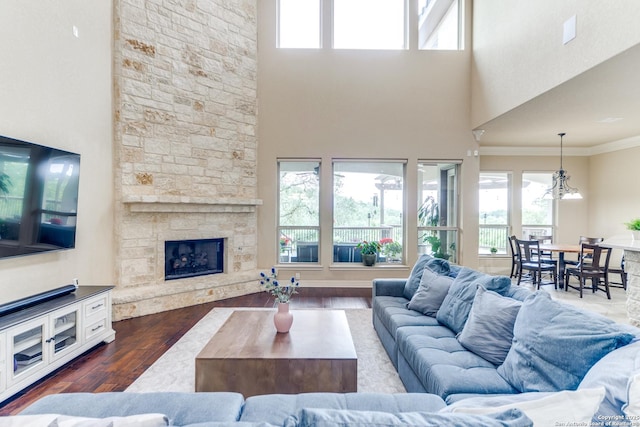 714 Ruidosa Downs, Helotes, TX 78023 - living room featuring dark wood finished floors, a stone fireplace, a towering ceiling, crown molding, and a chandelier