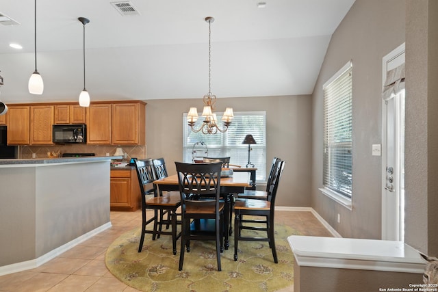 dining room with plenty of natural light, light tile patterned floors, a chandelier, vaulted ceiling, and baseboards