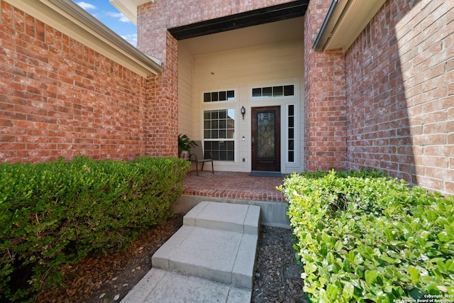doorway to property with brick siding and a porch