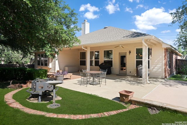 rear view of house featuring ceiling fan, a patio, a chimney, and roof with shingles