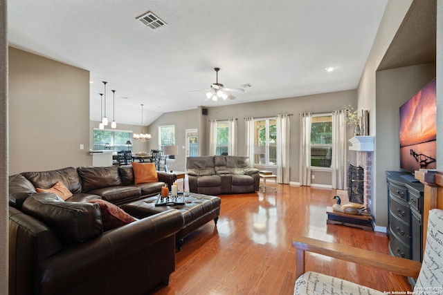 living room featuring ceiling fan, light wood-type flooring, a chandelier, vaulted ceiling, and baseboards