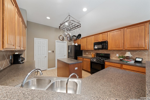 kitchen with black appliances, a sink, dark countertops, a kitchen island, and decorative backsplash