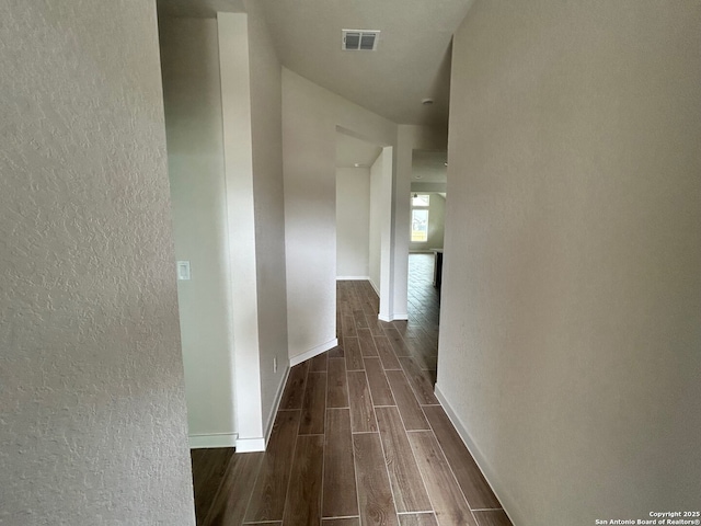 hall with wood tiled floors, a textured wall, and baseboards