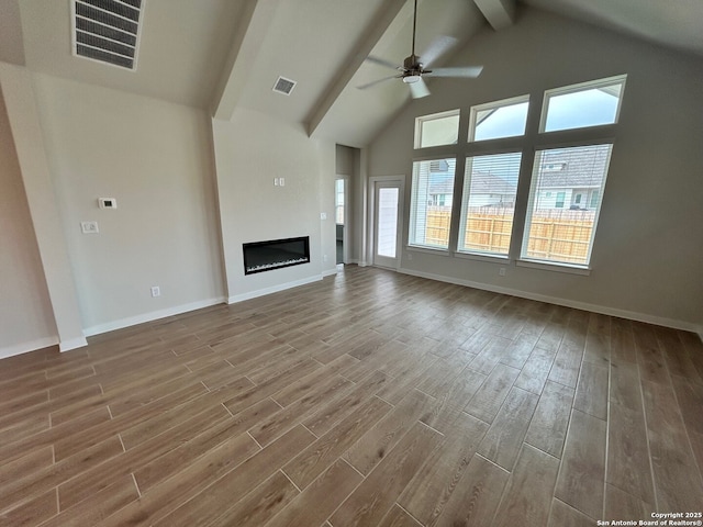 unfurnished living room with beamed ceiling, ceiling fan, wood finished floors, baseboards, and high vaulted ceiling