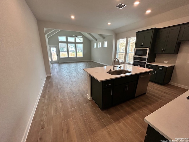 kitchen featuring appliances with stainless steel finishes, a sink, baseboards, wood finished floors, and light countertops