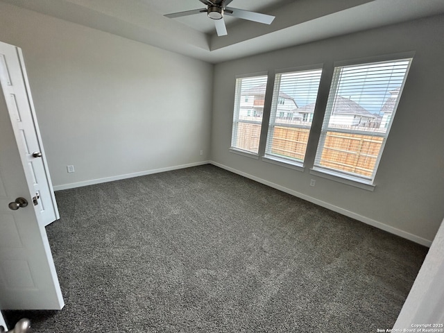empty room featuring ceiling fan, dark colored carpet, and baseboards