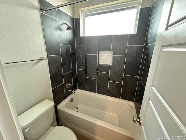 full bath featuring toilet, bathing tub / shower combination, and a textured wall
