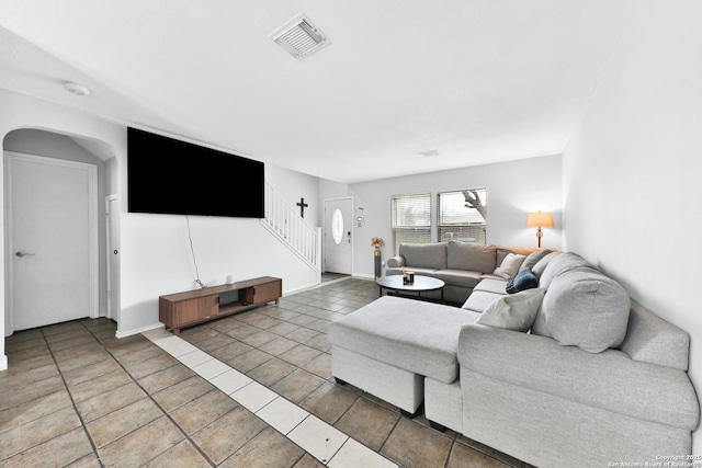 tiled living room with stairs, arched walkways, and baseboards
