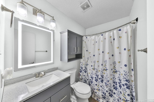bathroom featuring a textured ceiling, toilet, vanity, and curtained shower
