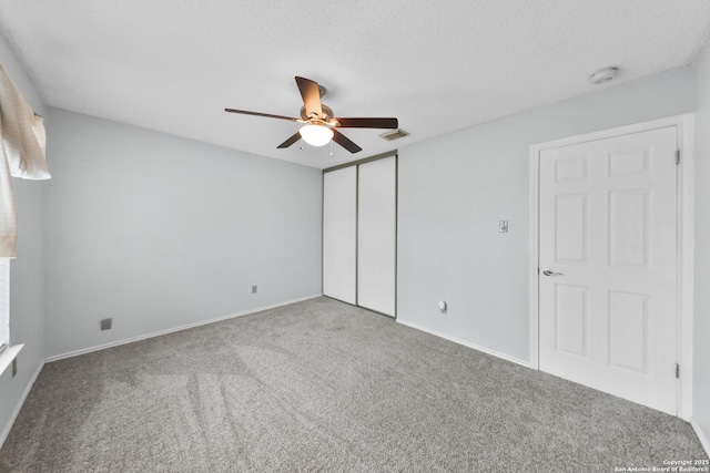 unfurnished bedroom with carpet flooring, a closet, a ceiling fan, baseboards, and a textured ceiling
