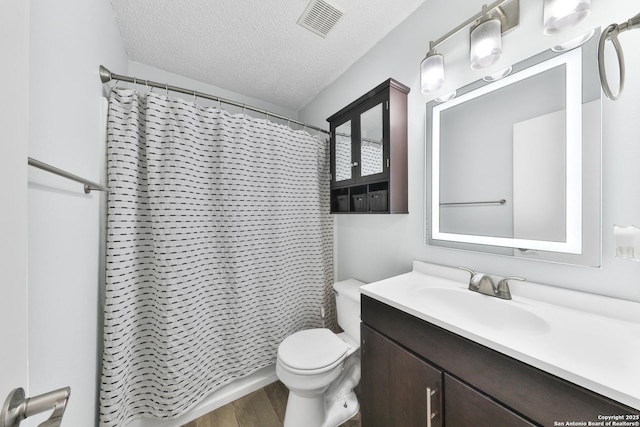 bathroom featuring wood finished floors, toilet, vanity, a textured ceiling, and a shower with curtain