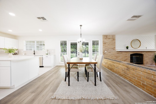 15031 Geronimo, San Antonio, TX 78254 - dining space featuring light wood-style floors, a brick fireplace, recessed lighting, and a chandelier