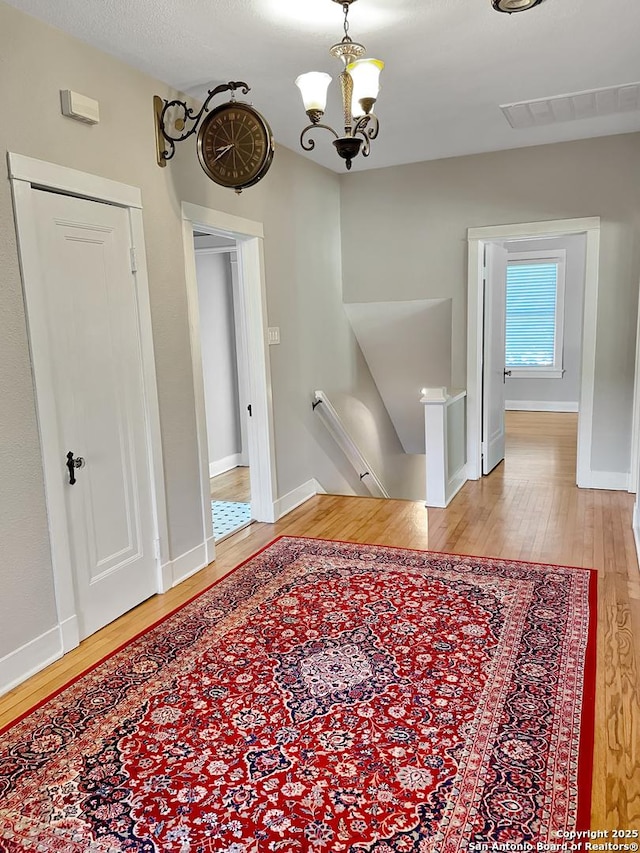 unfurnished dining area with wood finished floors, a chandelier, and baseboards