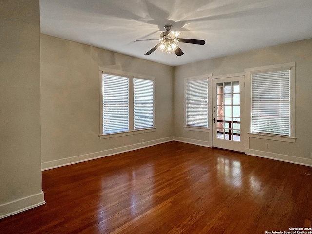 unfurnished room with baseboards, dark wood-type flooring, and a ceiling fan