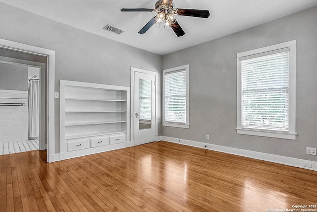 unfurnished bedroom featuring multiple windows, hardwood / wood-style flooring, baseboards, and ceiling fan