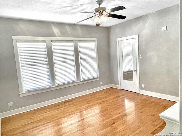 spare room with a ceiling fan, wood finished floors, and baseboards