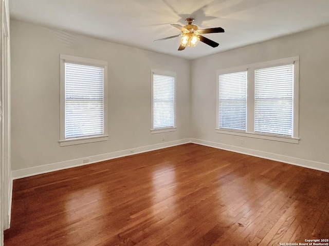 unfurnished room featuring dark wood-style floors, baseboards, healthy amount of natural light, and ceiling fan