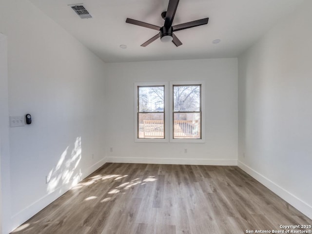 empty room featuring wood finished floors, baseboards, and a ceiling fan