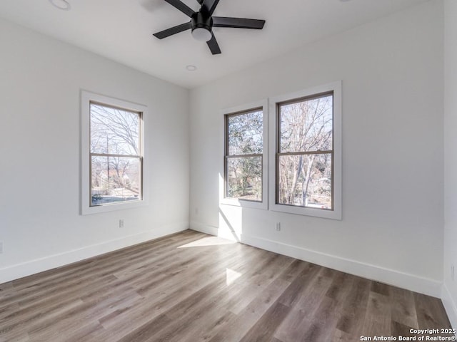 spare room with plenty of natural light, a ceiling fan, and baseboards