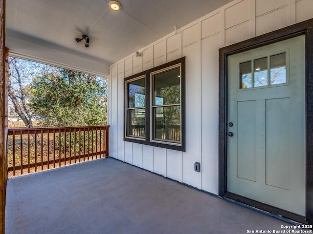 property entrance with board and batten siding and covered porch