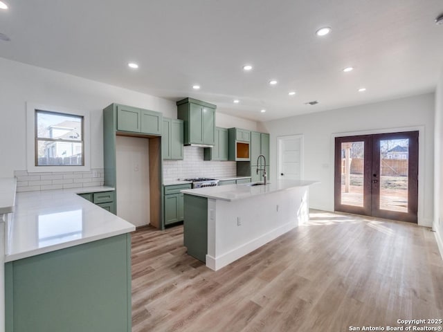 kitchen featuring green cabinets, french doors, light wood-style flooring, decorative backsplash, and recessed lighting
