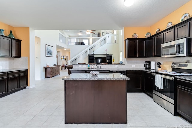 kitchen with stainless steel appliances, light stone countertops, decorative backsplash, light tile patterned floors, and a textured ceiling