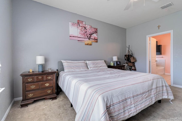 bedroom featuring light carpet, baseboards, ensuite bath, and a ceiling fan
