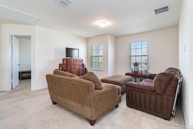 living area with attic access, light colored carpet, and baseboards