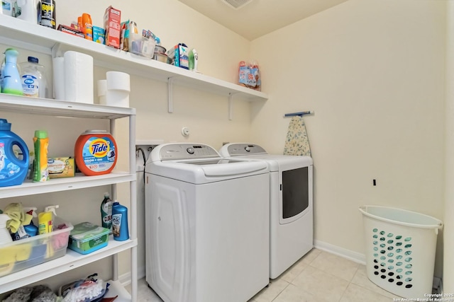 laundry area featuring independent washer and dryer, light tile patterned floors, and baseboards