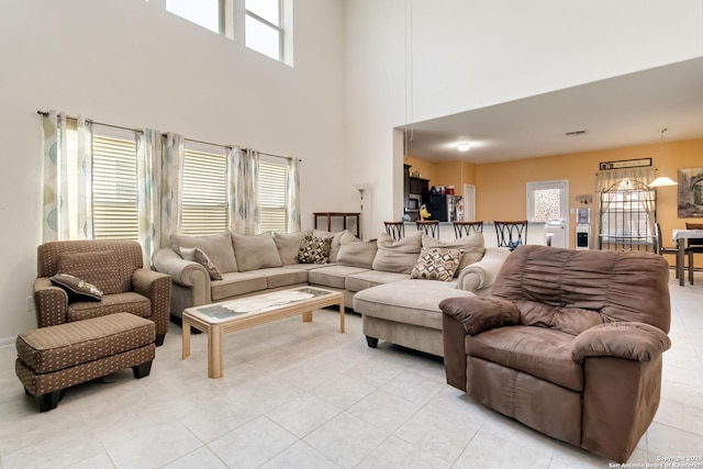 living area with plenty of natural light, light tile patterned floors, and a high ceiling