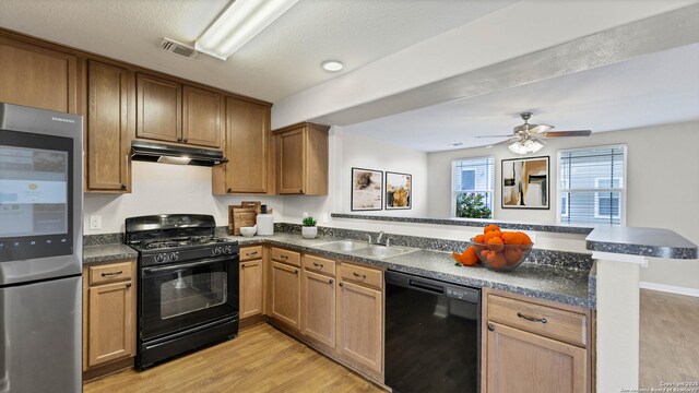 220 Trestle Tree Unit 112, San Marcos, TX 78666 - kitchen with black appliances, a peninsula, under cabinet range hood, a sink, and dark countertops