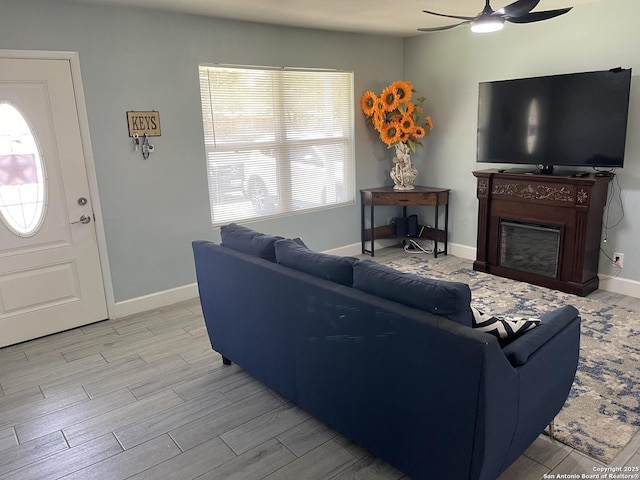living area featuring ceiling fan, light wood-style flooring, plenty of natural light, and a fireplace