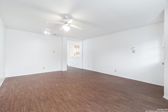 spare room with a ceiling fan, dark wood-type flooring, a textured ceiling, and baseboards