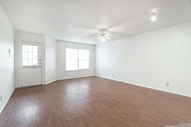 unfurnished living room with ceiling fan, wood finished floors, plenty of natural light, a textured ceiling, and baseboards