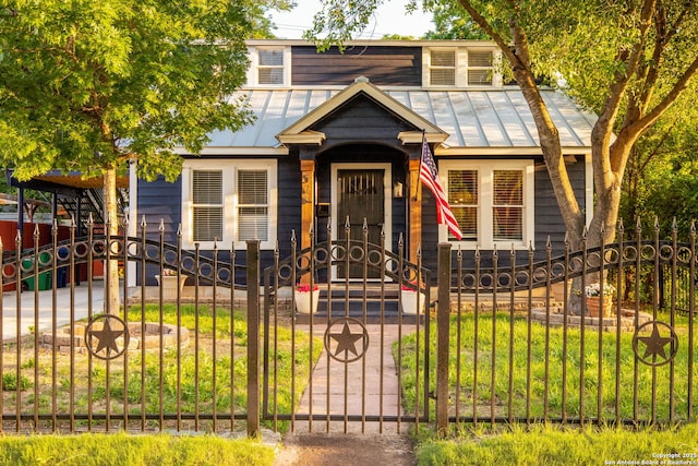 view of front of home with a standing seam roof, a fenced front yard, and metal roof
