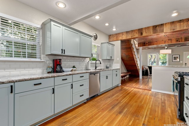 kitchen featuring stainless steel appliances, backsplash, a sink, light wood-style floors, and recessed lighting