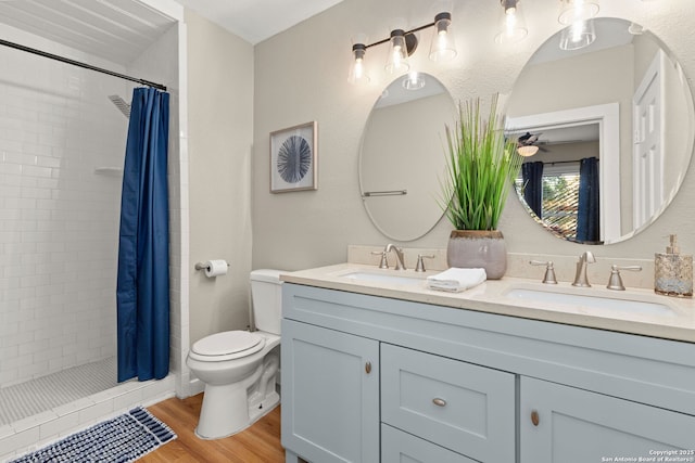 full bathroom with toilet, wood finished floors, double vanity, and a shower stall