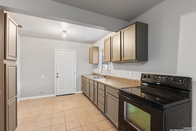 kitchen featuring black electric range oven, a sink, light tile patterned flooring, and baseboards