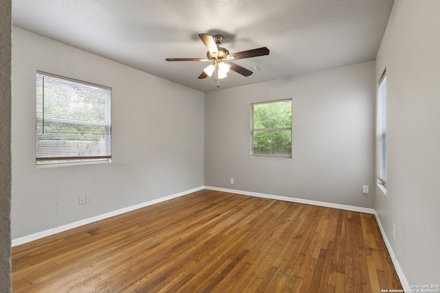 spare room featuring wood finished floors, baseboards, and a ceiling fan