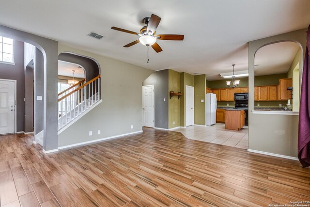 9007 Burnt Peak, Helotes, TX 78023 - unfurnished living room with arched walkways, ceiling fan, light wood-style floors, and healthy amount of natural light