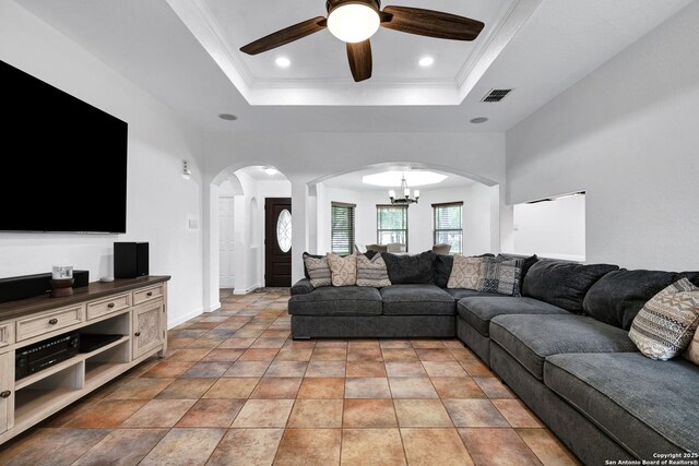 living room featuring arched walkways, a tray ceiling, a chandelier, ceiling fan, and baseboards