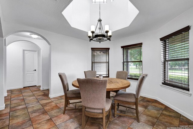 dining room featuring a chandelier, arched walkways, and baseboards