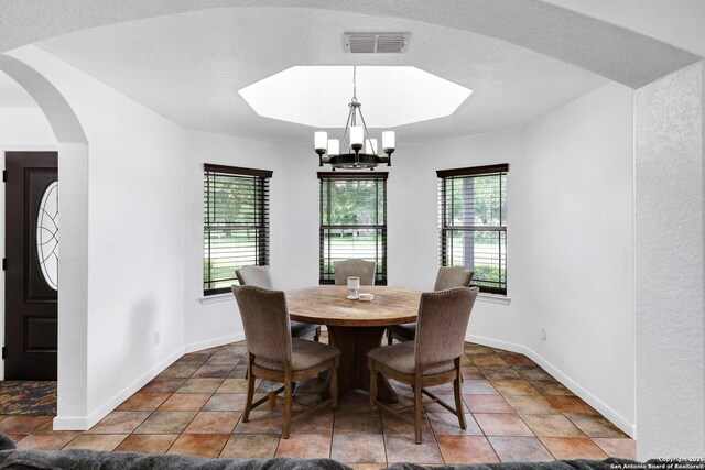 dining space with a chandelier, baseboards, arched walkways, and stone finish floors
