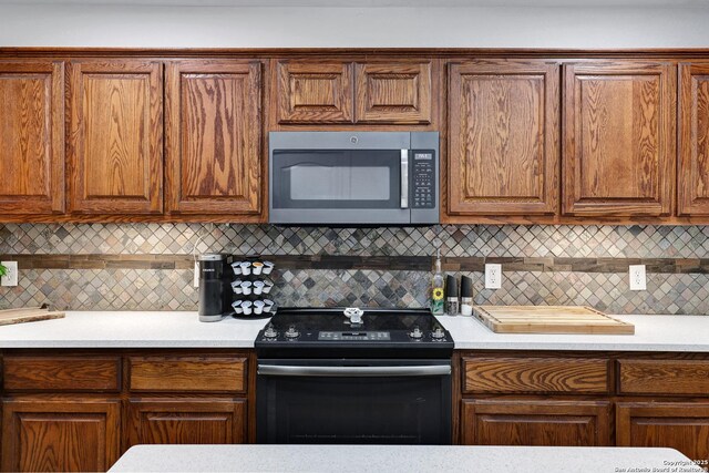 kitchen featuring stainless steel microwave, electric range, light countertops, and backsplash