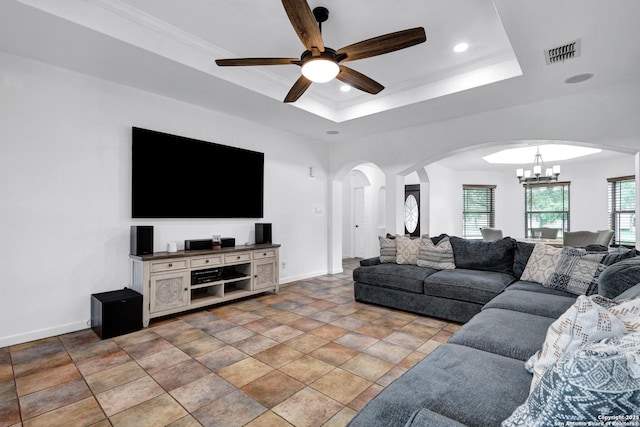 living area with arched walkways, a chandelier, a ceiling fan, baseboards, and a tray ceiling