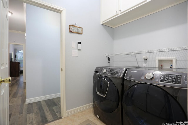 laundry room with cabinet space, washing machine and clothes dryer, baseboards, and wood finished floors