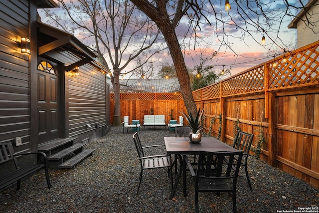 patio terrace at dusk with entry steps, a fenced backyard, and outdoor dining space