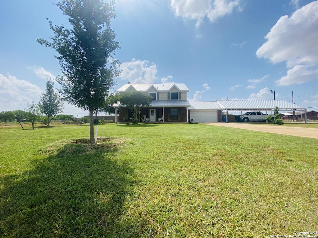 traditional-style home with concrete driveway, a garage, a front yard, metal roof, and a carport