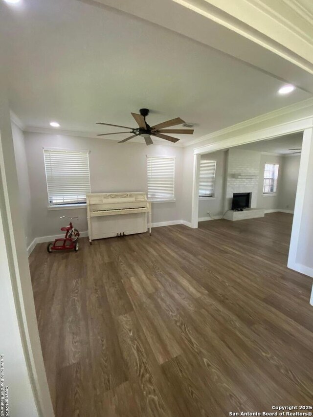 606 S Phelps St, Dilley, TX 78017 - unfurnished living room featuring crown molding, baseboards, ceiling fan, wood finished floors, and a fireplace