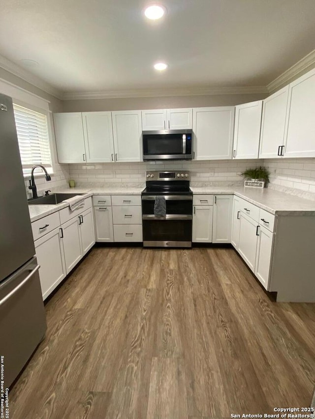 606 S Phelps St, Dilley, TX 78017 - kitchen with stainless steel appliances, a sink, decorative backsplash, white cabinetry, and ornamental molding